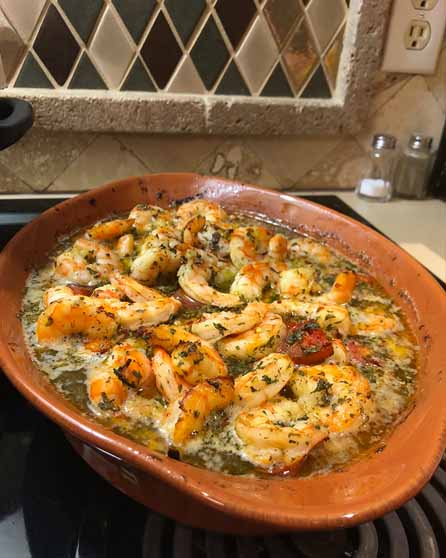 A serving of spicy baked shrimp spooned over thin spaghetti.